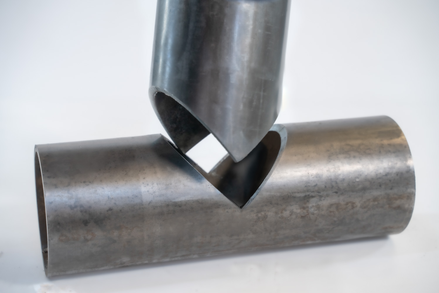 Two steel tubes laser-cut with mitres fitting into a T-joint before welding