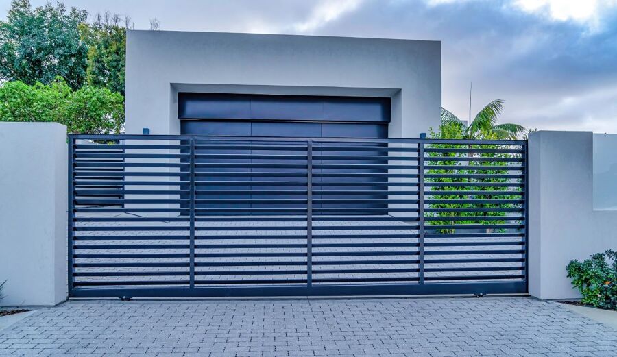 Puerta corredera de exterior motorizada de acero con lamas horizontales a la entrada de un chalet